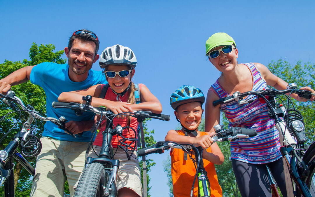Aktiivinen perhe pyöräilemässä aurinkoisena sunnuntaipäivänä.