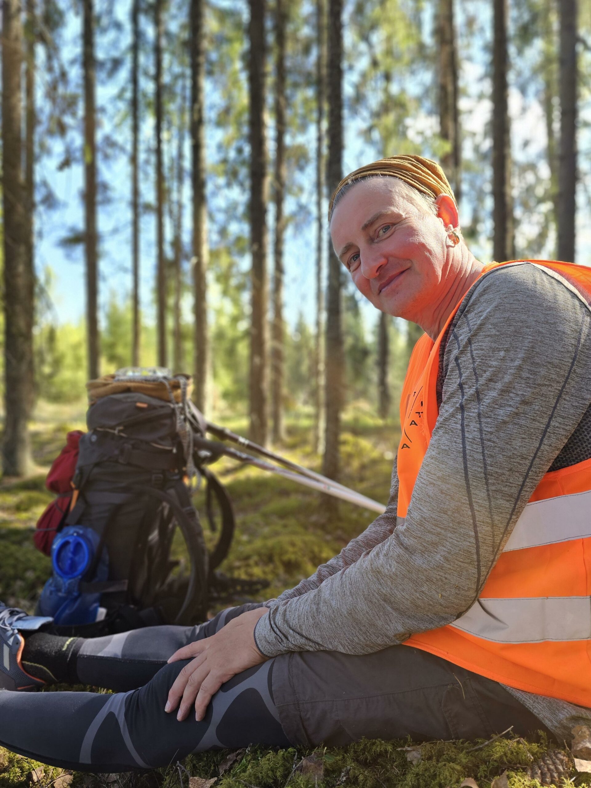Kimmo Ylönen oranssissa huomioliivissä metsässä.